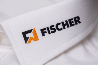 Gesticktes Firmenlogo FISCHER auf Hemdkragen – hochwertige Logo Stickerei für Businesshemden Weißer Hemdkragen mit aufgesticktem FISCHER Logo in Schwarz und Orange – Beispiel für individuelle Stickerei auf Business- und Firmenhemden